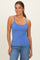 woman wearing a royal blue camisole top with thin straps, smiling and posed in front of a neutral background