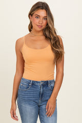 woman wearing a light orange spaghetti strap tank top and high-waisted blue jeans