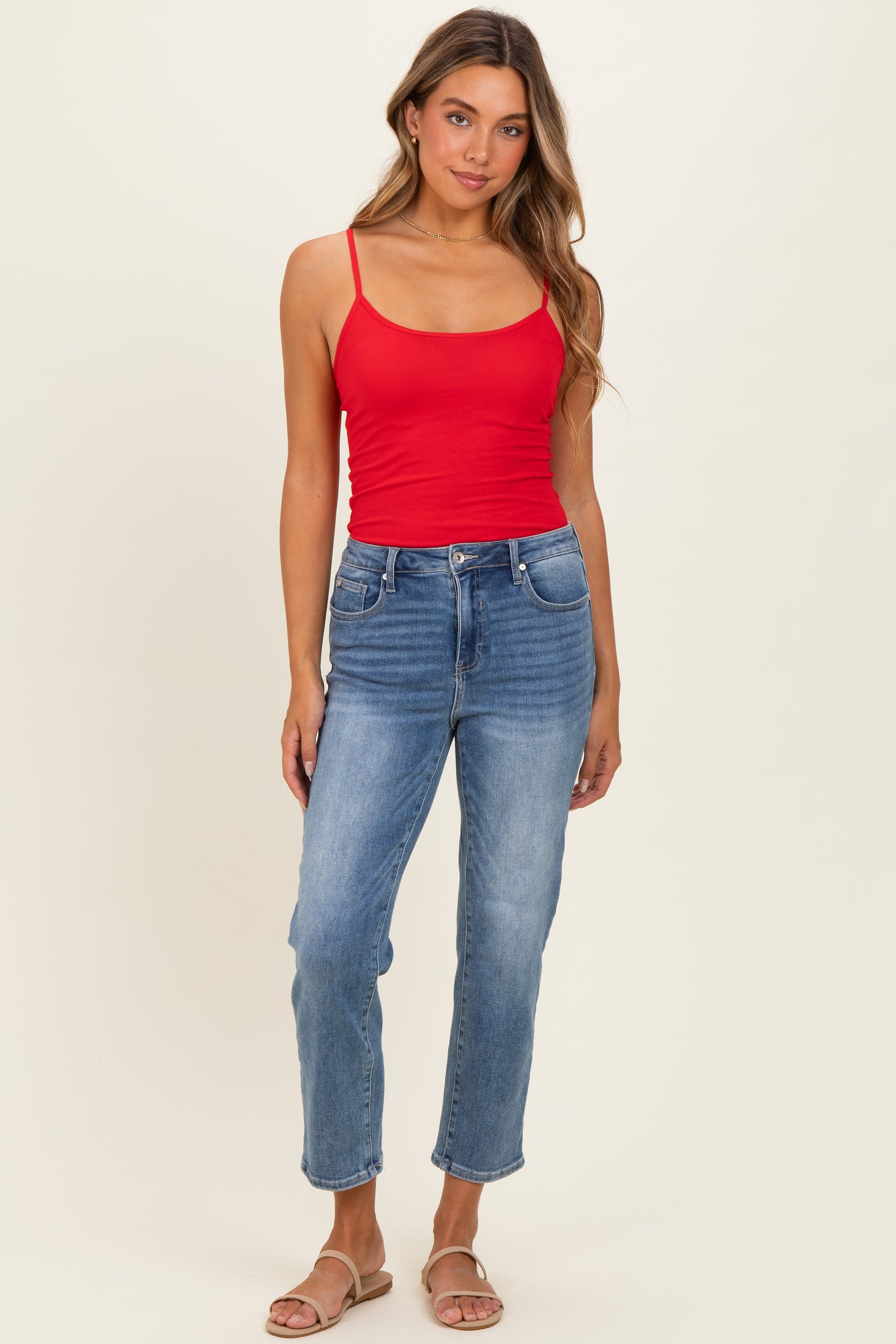 woman wearing a red spaghetti strap tank top and light blue straight leg jeans with sandals