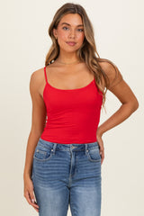 woman wearing a red fitted camisole top and blue high-waisted jeans