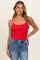 woman wearing a red fitted camisole top and blue high-waisted jeans