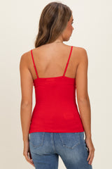 woman wearing a red fitted camisole top with adjustable straps and blue skinny jeans from the back