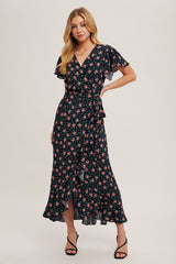 woman wearing a black floral wrap dress with ruffled sleeves and a high low hemline, standing confidently