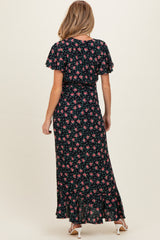 woman wearing a black floral maternity maxi dress with short flutter sleeves and a ruffled hem