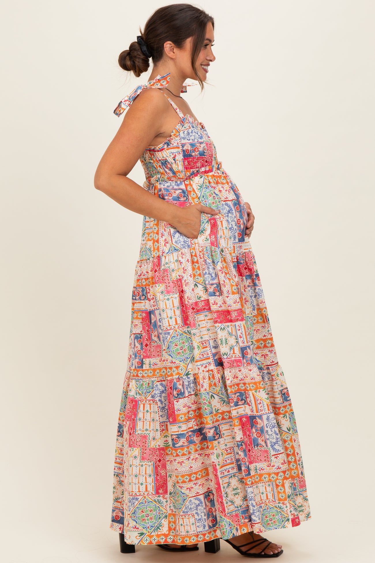 woman wearing a colorful floral print maternity maxi dress with a baby bump and side pockets