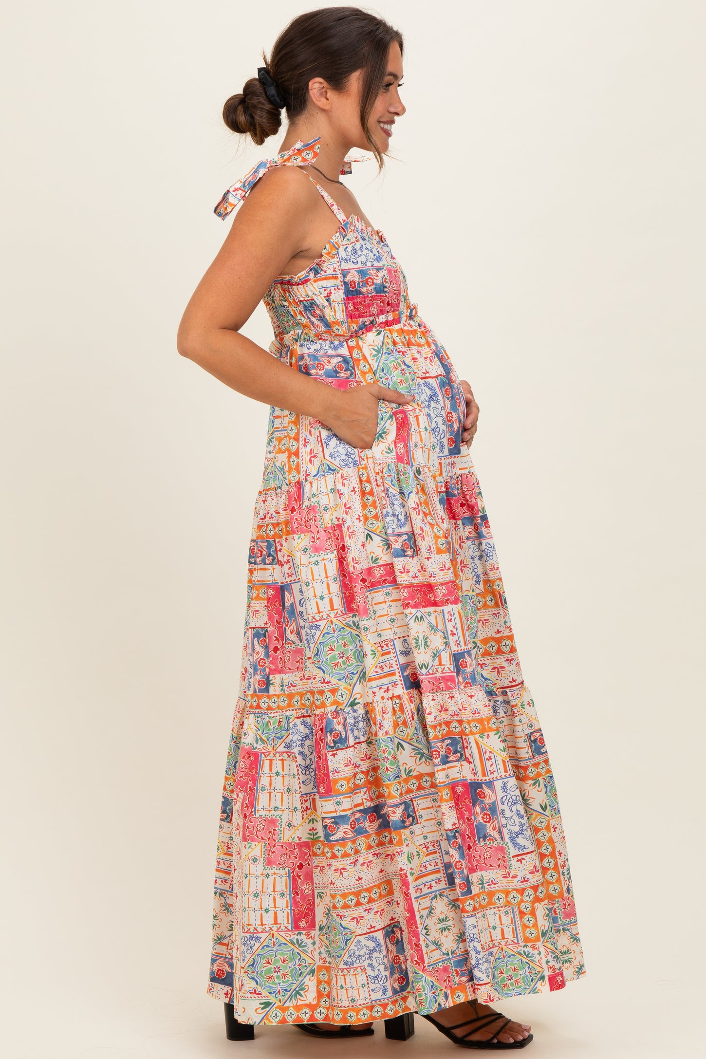 woman wearing a colorful floral print maternity maxi dress with a baby bump and side pockets