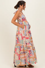 woman wearing a colorful floral print maternity maxi dress with a baby bump and side pockets