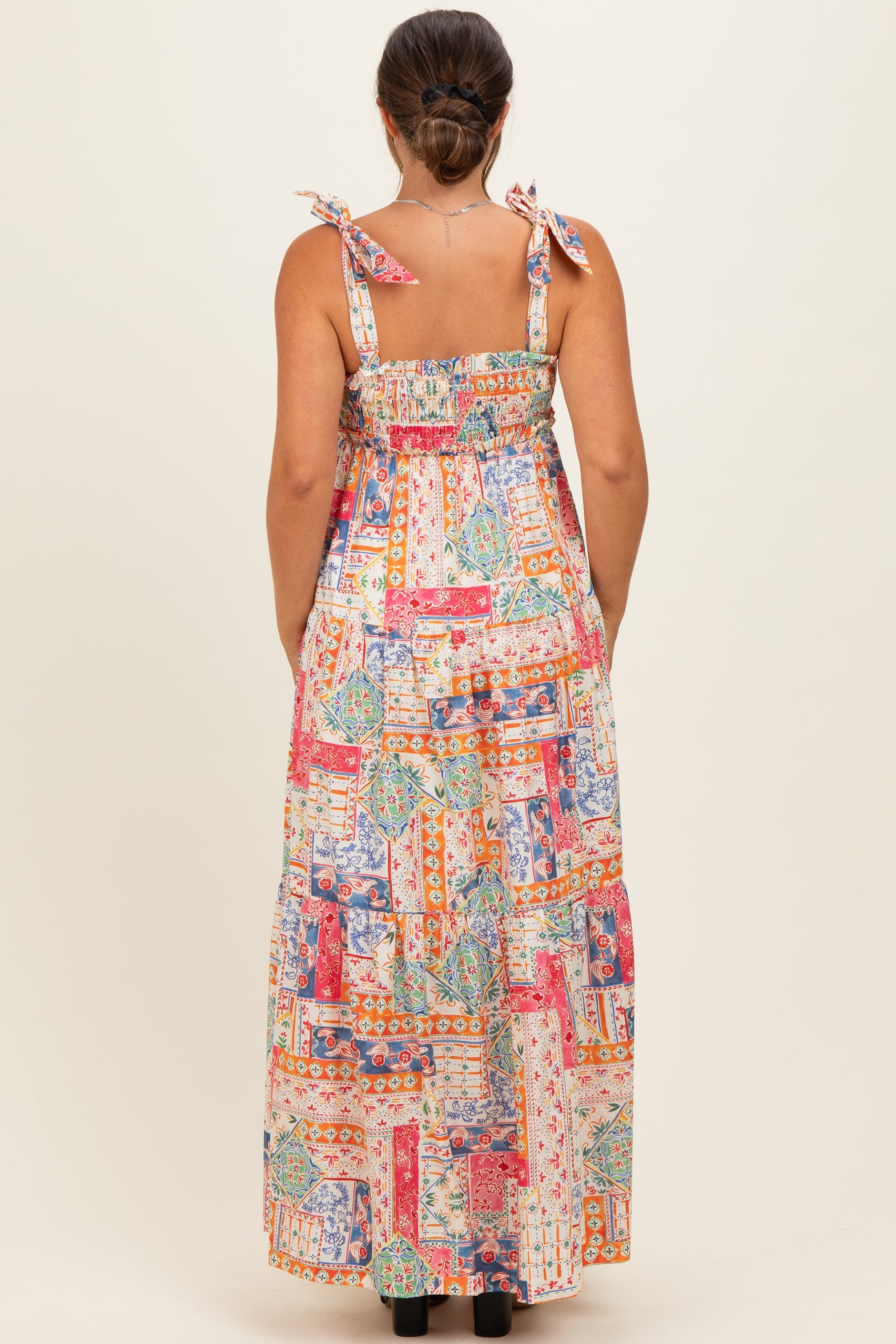 woman wearing a colorful patterned maternity maxi dress with adjustable tie straps, showing the back view