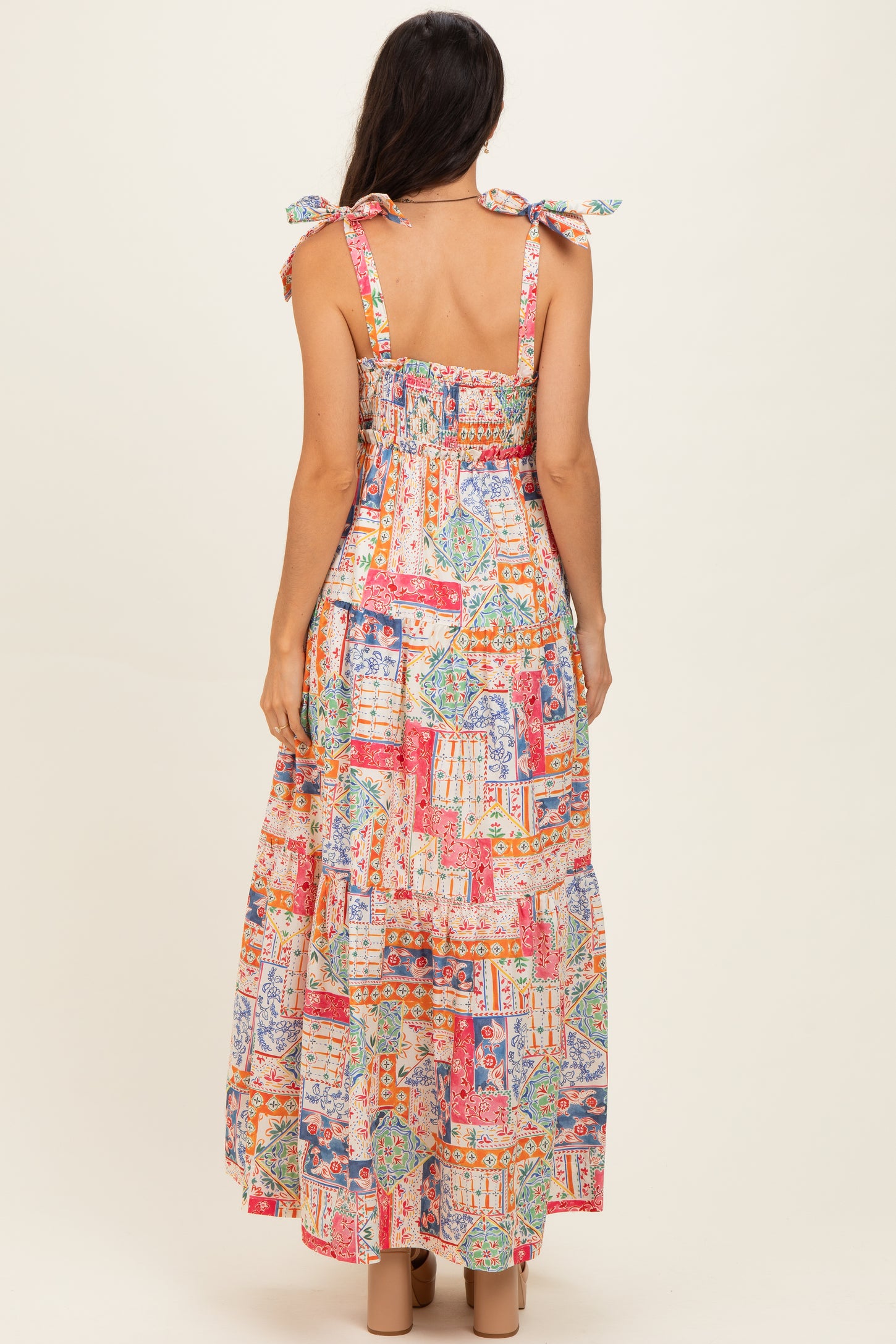woman wearing a colorful, patterned maxi dress with tie shoulder straps and a smocked back