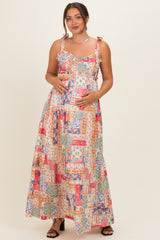 woman wearing a colorful floral maternity maxi dress with ruffled straps and holding her baby bump