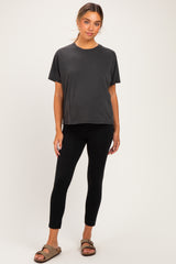 woman wearing a black maternity top and black maternity leggings, standing with a relaxed pose