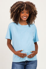 woman wearing a light blue short sleeve maternity top and holding her baby bump