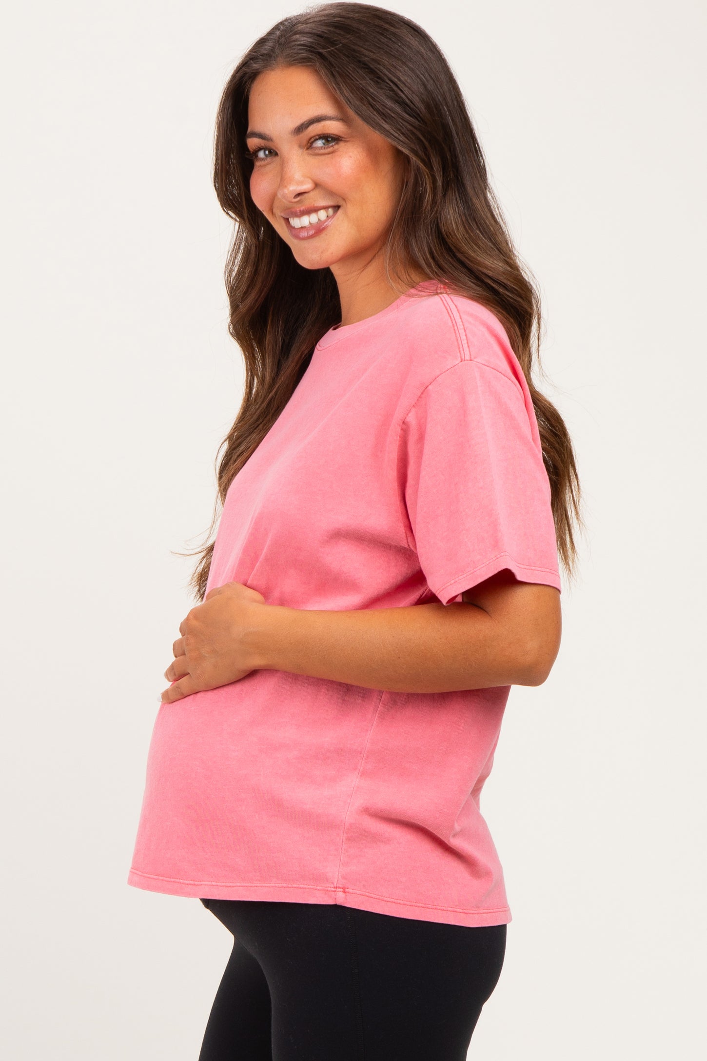 woman wearing a pink maternity t-shirt and holding her baby bump