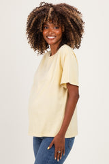 woman wearing a light yellow maternity t-shirt and showcasing her baby bump