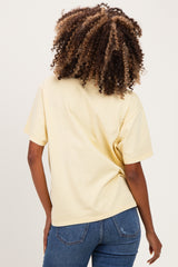 woman wearing a yellow short sleeve maternity top with a relaxed fit and back view, paired with jeans