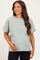 woman wearing a sage green short sleeve maternity t-shirt and holding her baby bump