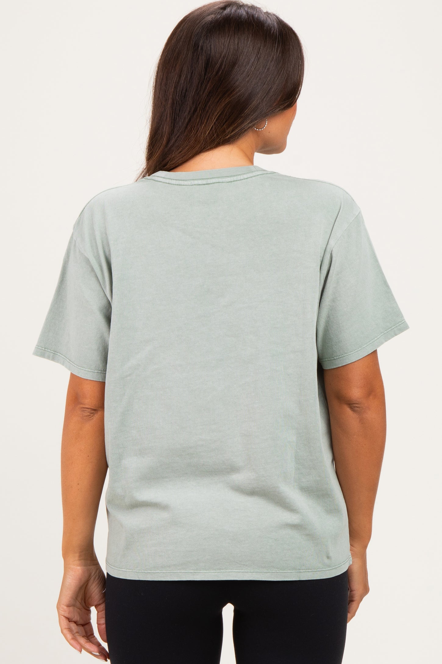 woman wearing a light green oversized maternity t-shirt from the back, paired with black leggings