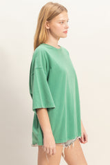 woman wearing an oversized green short sleeve t-shirt paired with distressed denim shorts