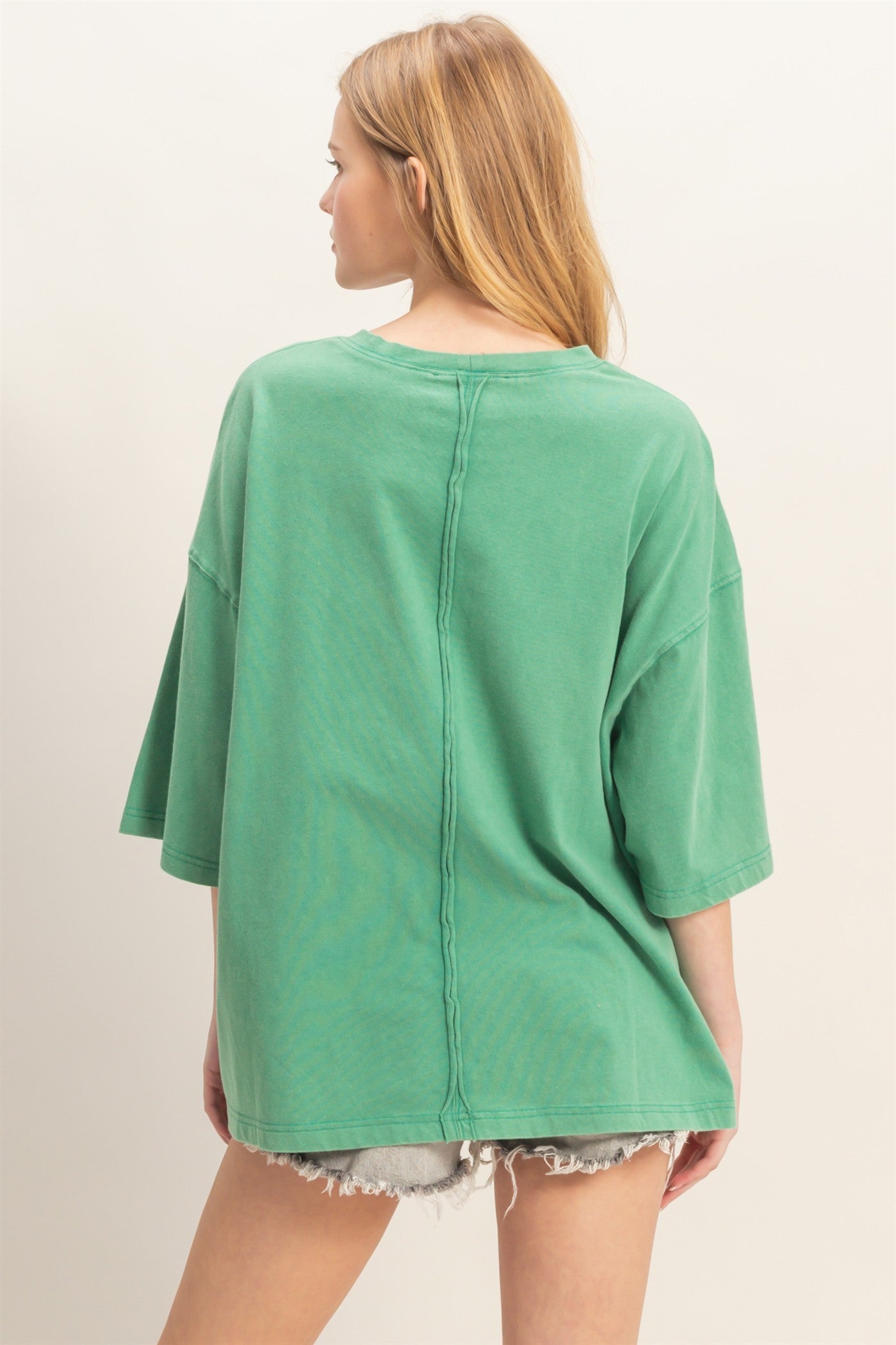 woman wearing a loose-fitting green oversized t-shirt with dropped shoulders and a raw hem
