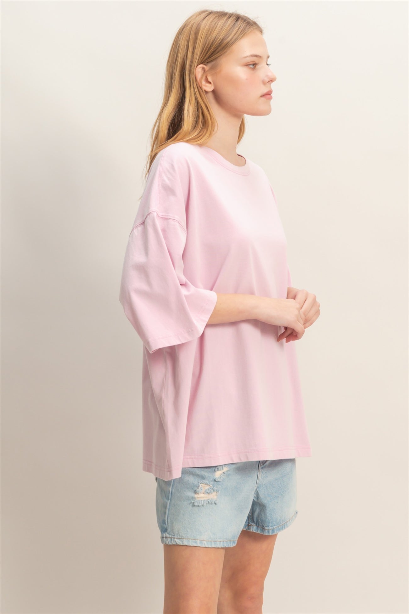 woman wearing a light pink oversized t-shirt and distressed denim shorts