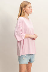 woman wearing a light pink oversized t-shirt and distressed denim shorts