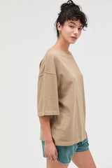 woman wearing a tan oversized t-shirt with short sleeves and styled with teal shorts