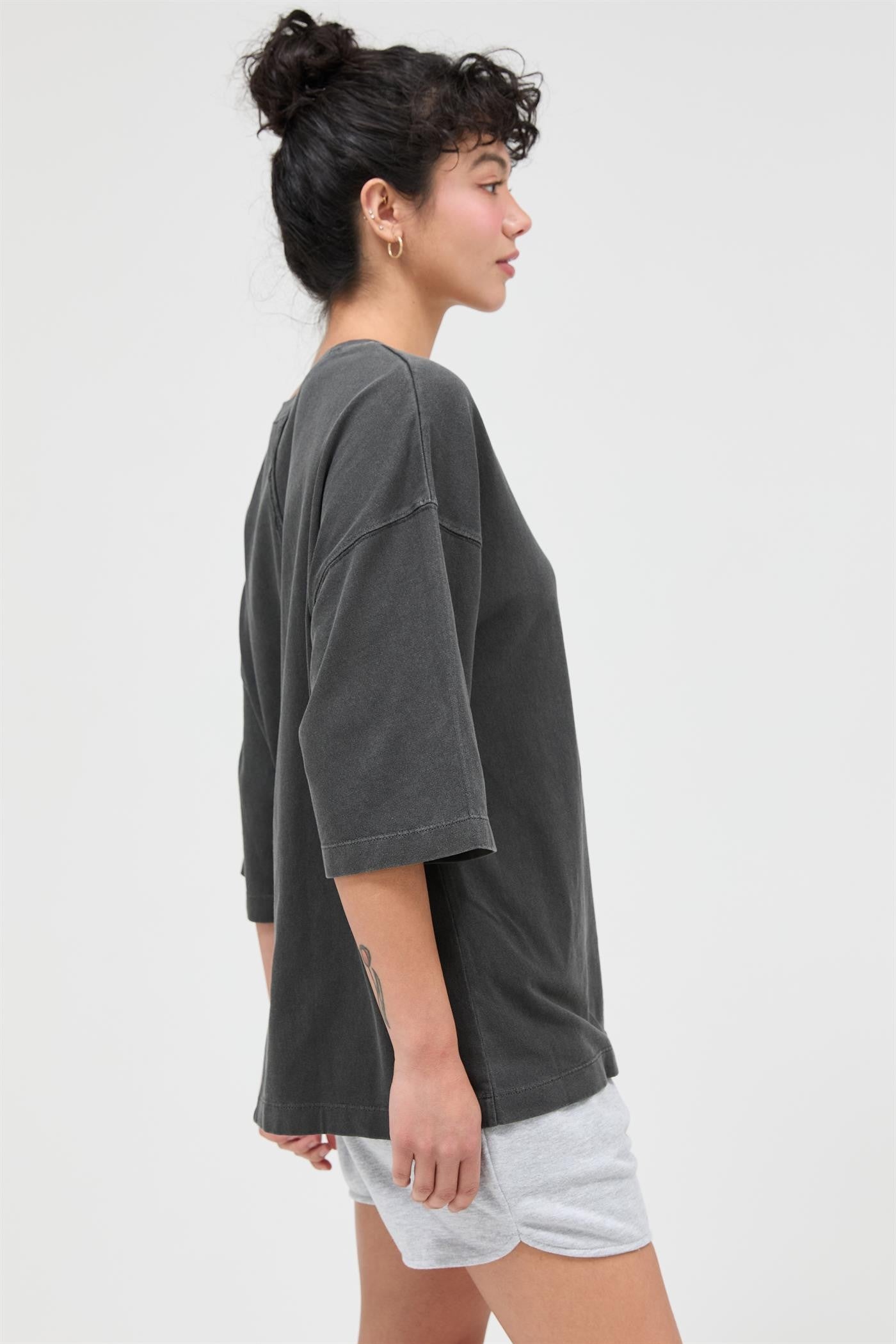 woman wearing a gray oversized short sleeve t-shirt and light gray shorts, side view