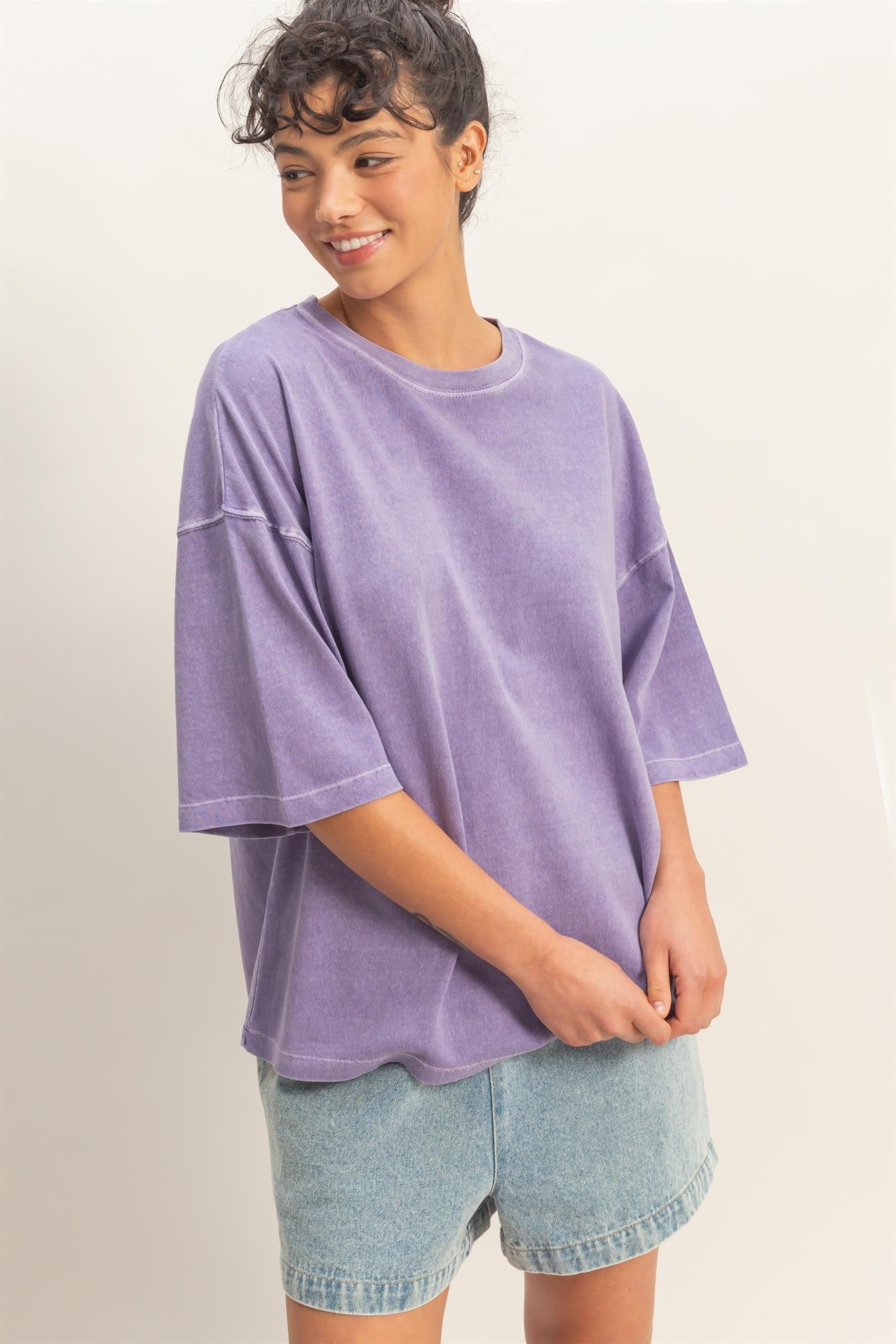 woman wearing a relaxed fit purple oversized t-shirt and light blue denim shorts
