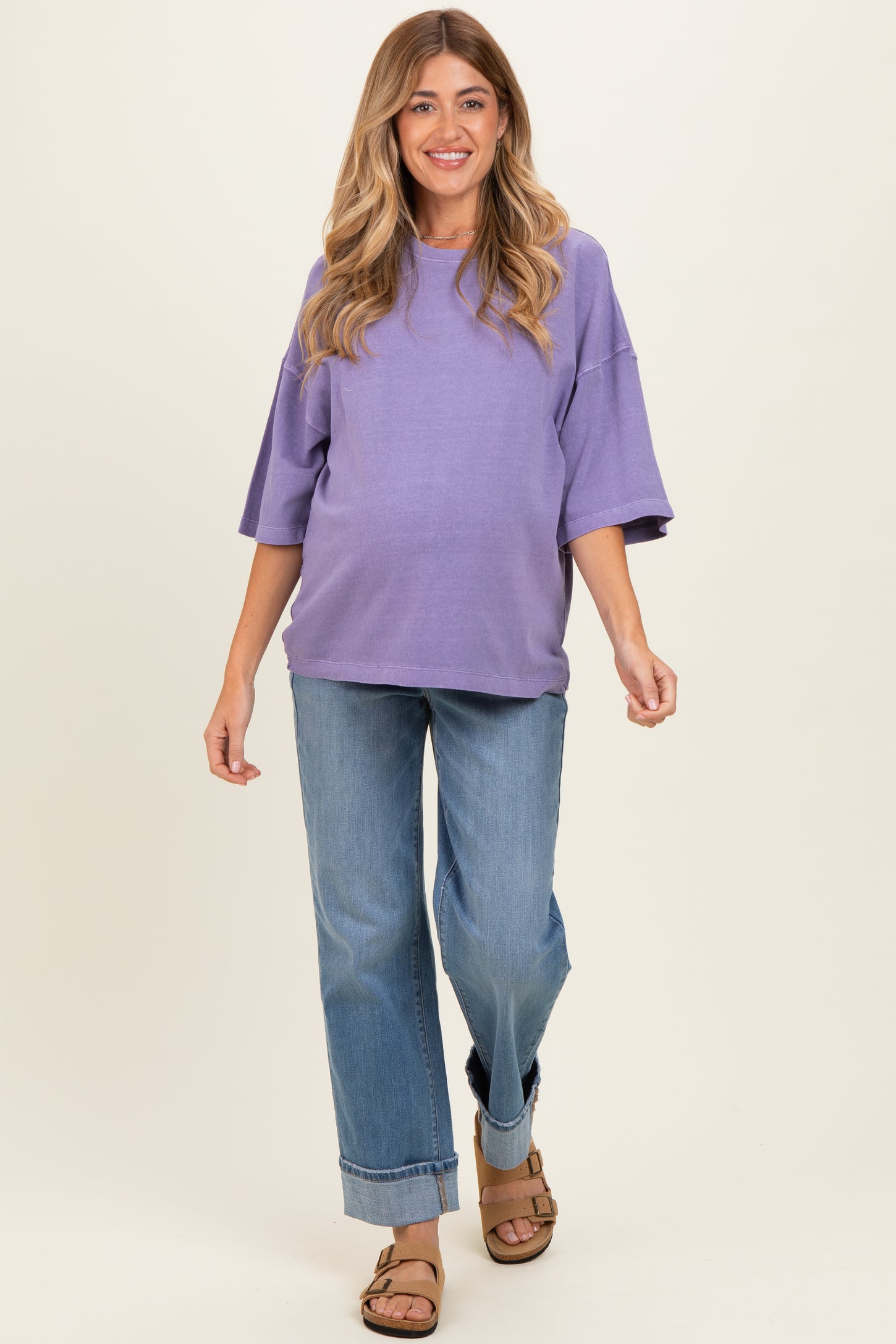 woman wearing a purple oversized maternity sweatshirt and jeans, showcasing her baby bump while walking