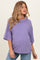 woman wearing a purple oversized maternity top and showing her baby bump