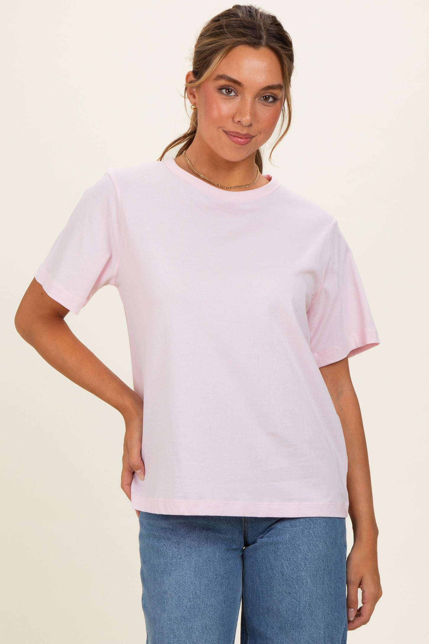 woman wearing a pink short sleeve t-shirt paired with blue jeans