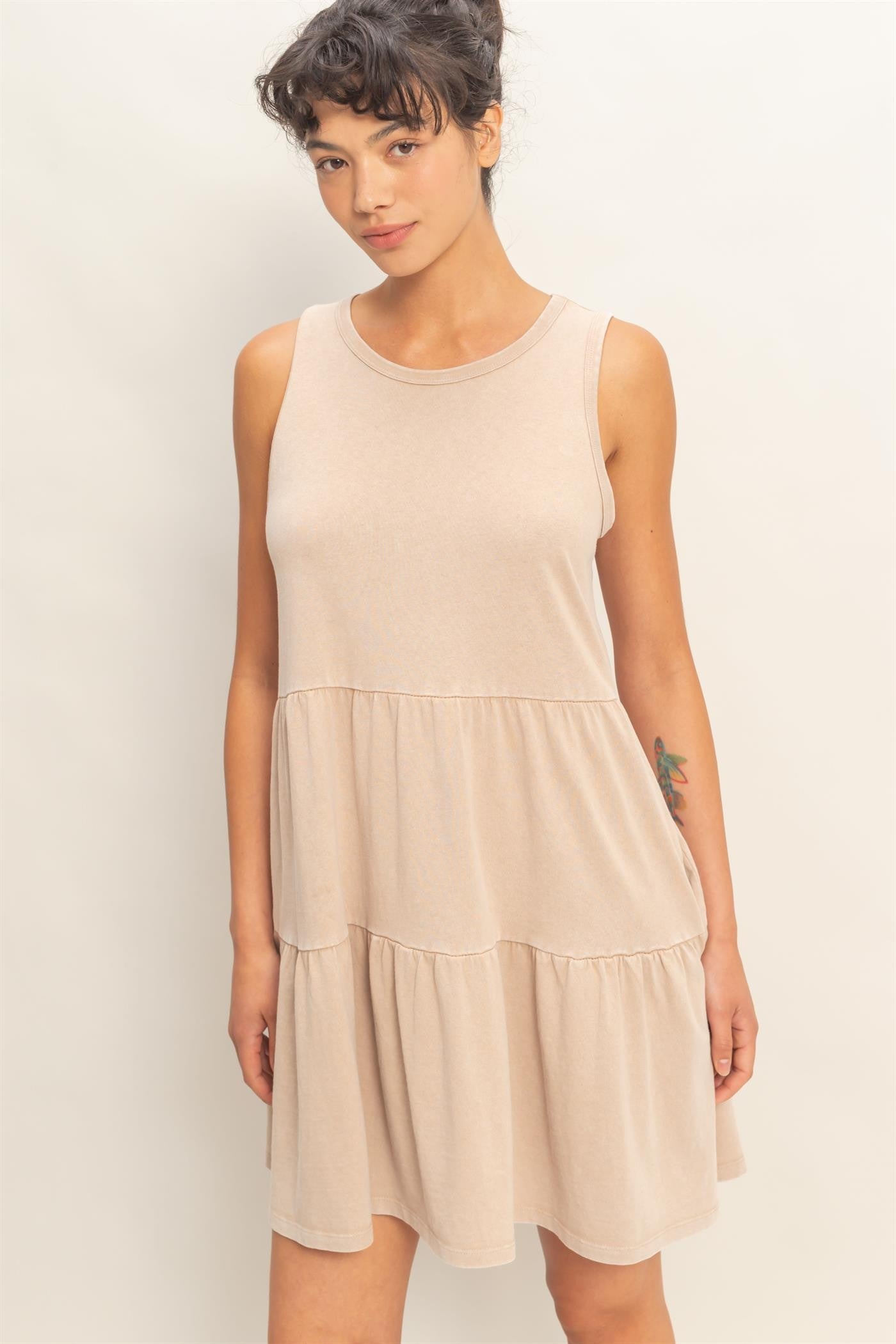 woman wearing a sleeveless beige tiered dress with a loose fit and round neckline