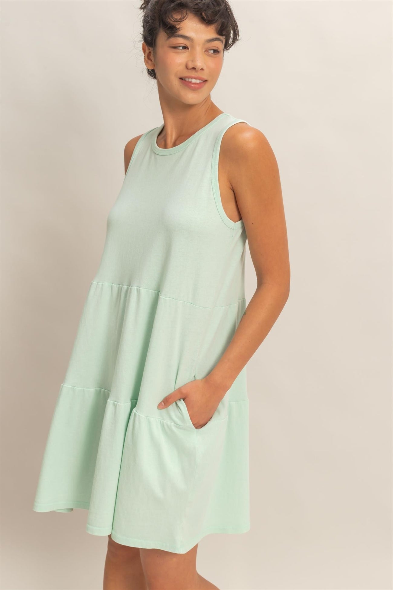 woman wearing a mint green sleeveless tiered dress with pockets
