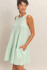woman wearing a mint green sleeveless tiered dress with pockets