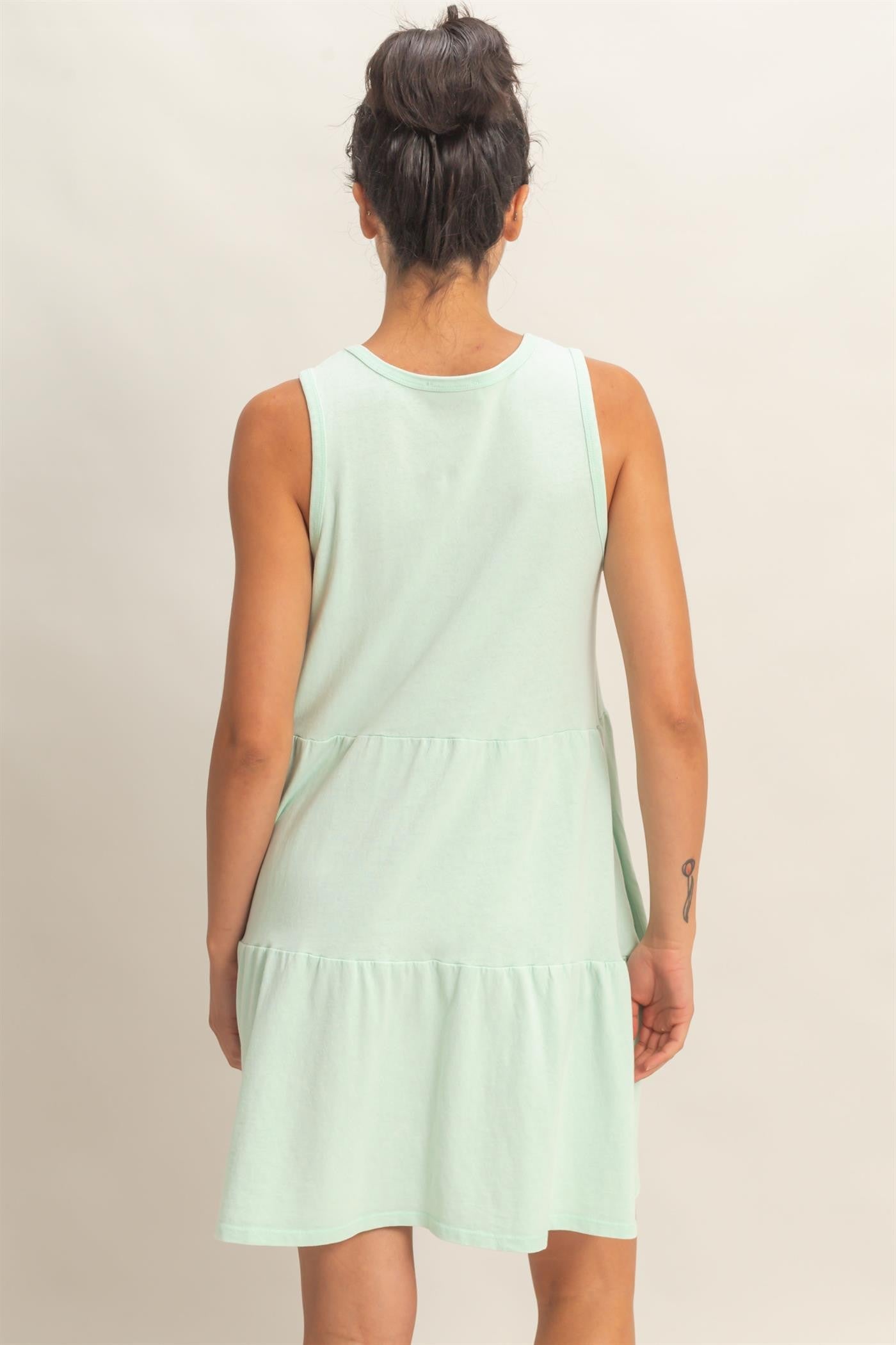 woman wearing a mint green sleeveless tiered mini dress, viewed from the back