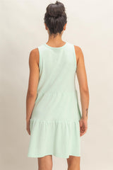 woman wearing a mint green sleeveless tiered mini dress, viewed from the back