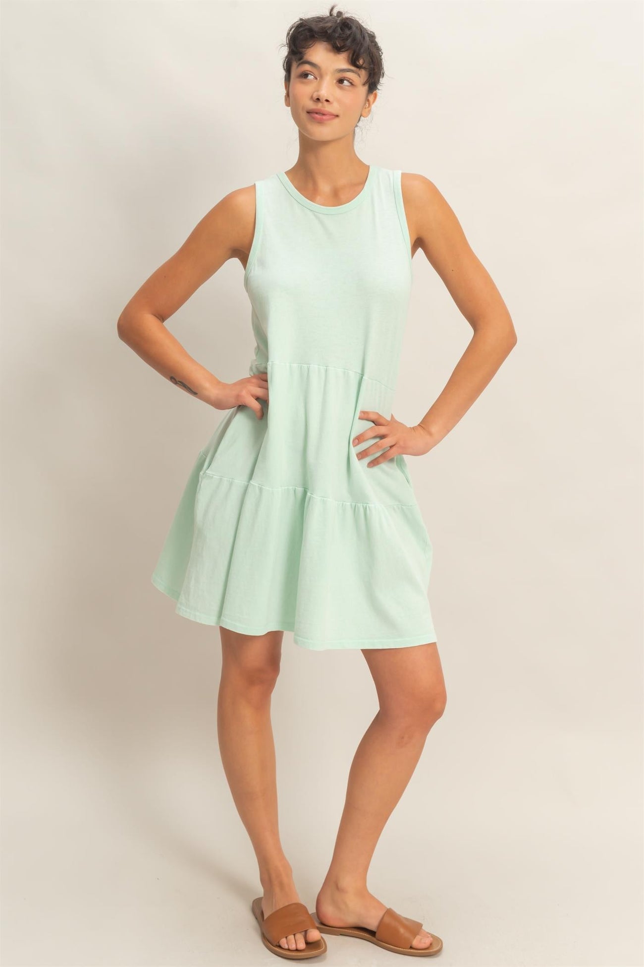 woman wearing a mint green sleeveless tiered dress and brown slide sandals