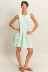 woman wearing a mint green sleeveless tiered dress and brown slide sandals
