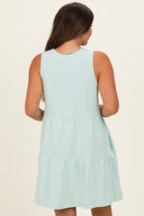 woman wearing a mint green sleeveless maternity dress with a tiered skirt, showing the back view