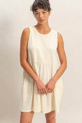 woman wearing a cream sleeveless tiered dress with a relaxed fit