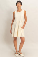 woman wearing a cream sleeveless tiered dress with pockets