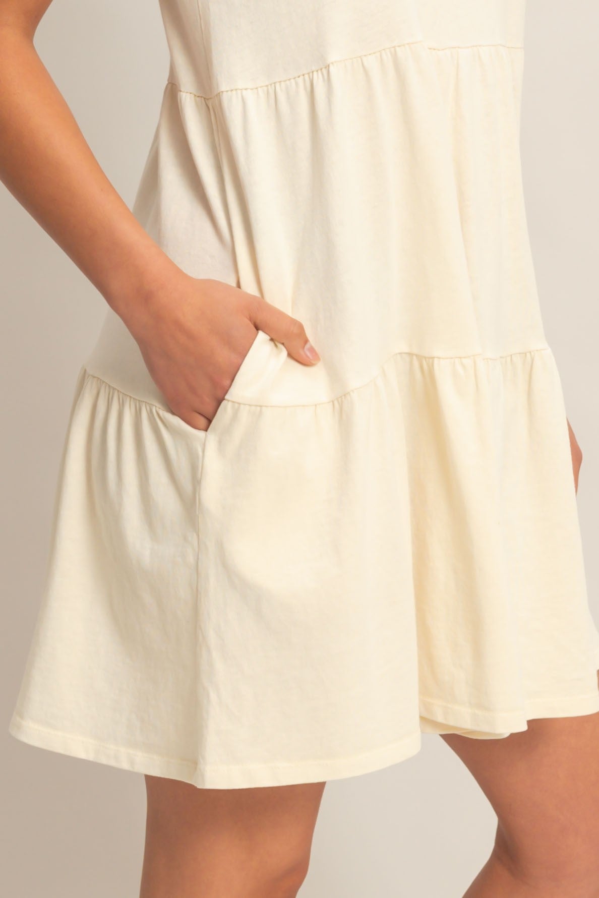 woman wearing a light yellow short sleeve dress with a tiered design and pockets