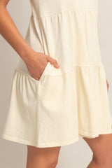 woman wearing a light yellow short sleeve dress with a tiered design and pockets