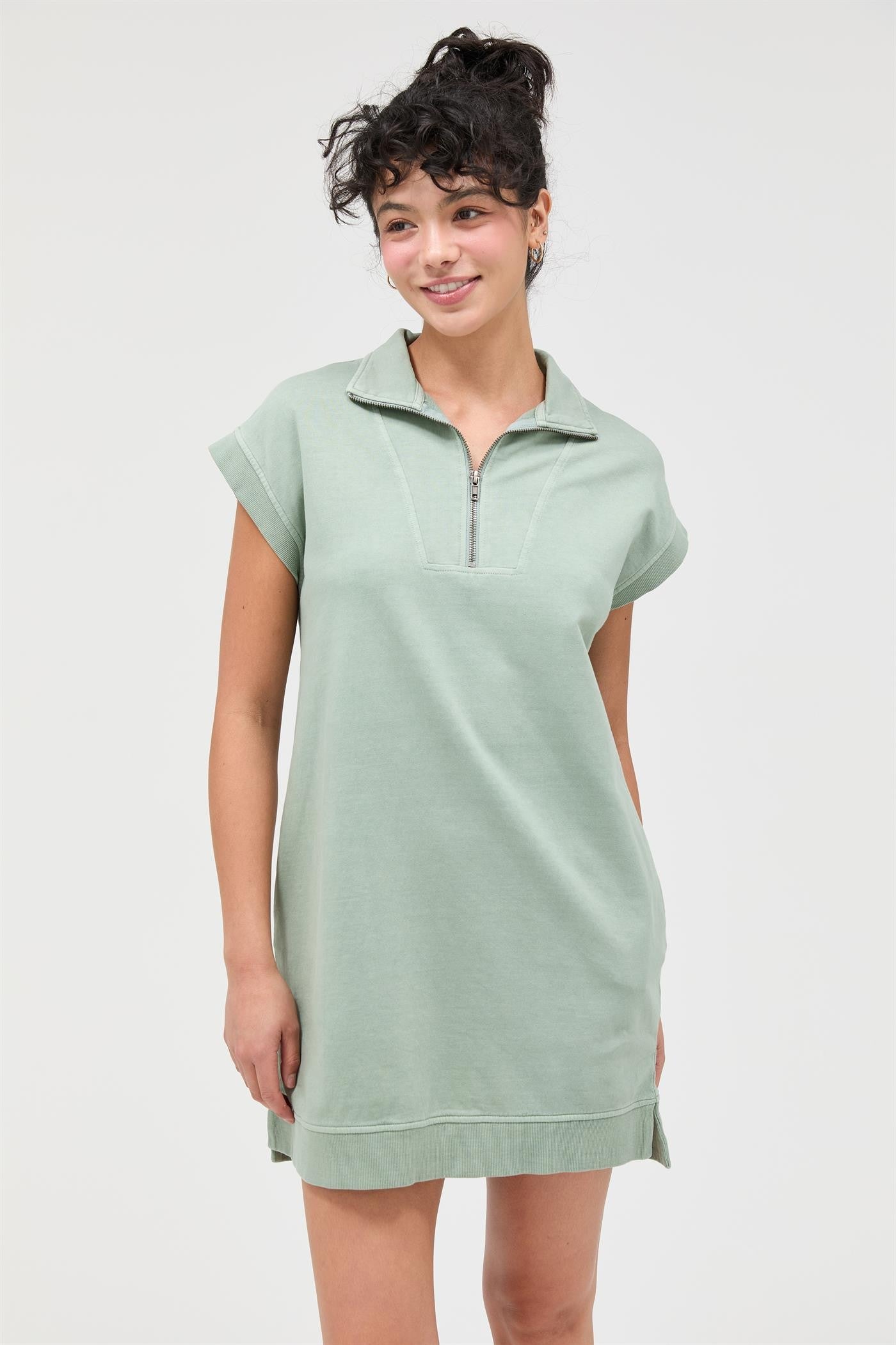 woman wearing a light green short sleeve zip-up dress with a collar and side slits