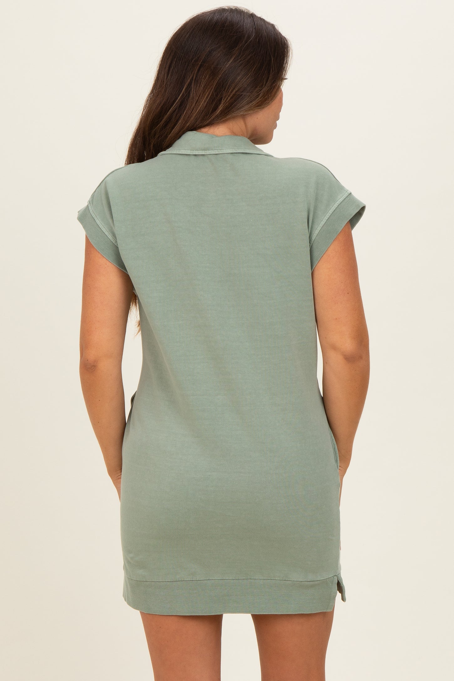 woman wearing a green short sleeve maternity polo dress from the back