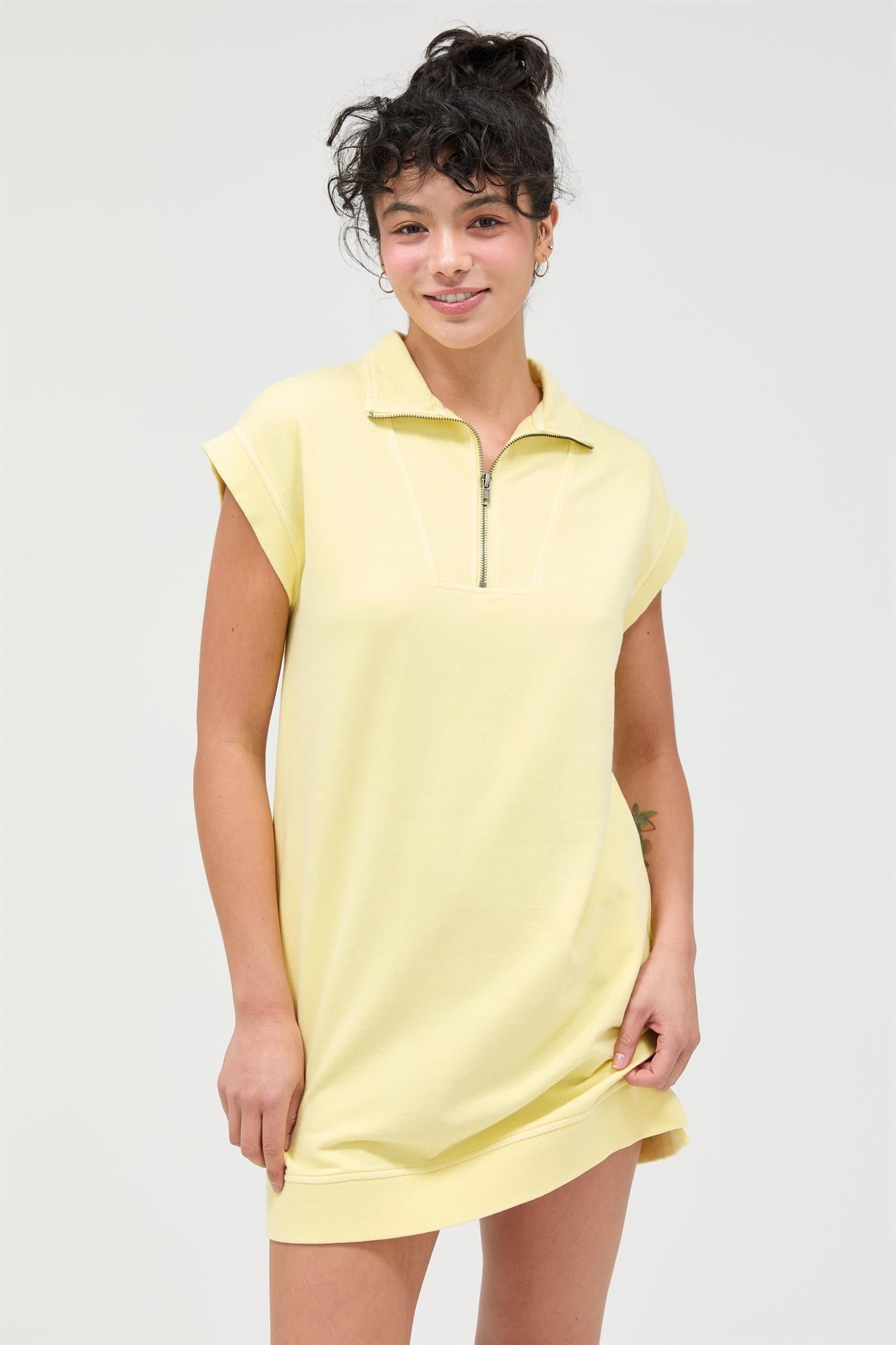 woman wearing a light yellow zip-up short sleeve dress with a relaxed fit and a casual style