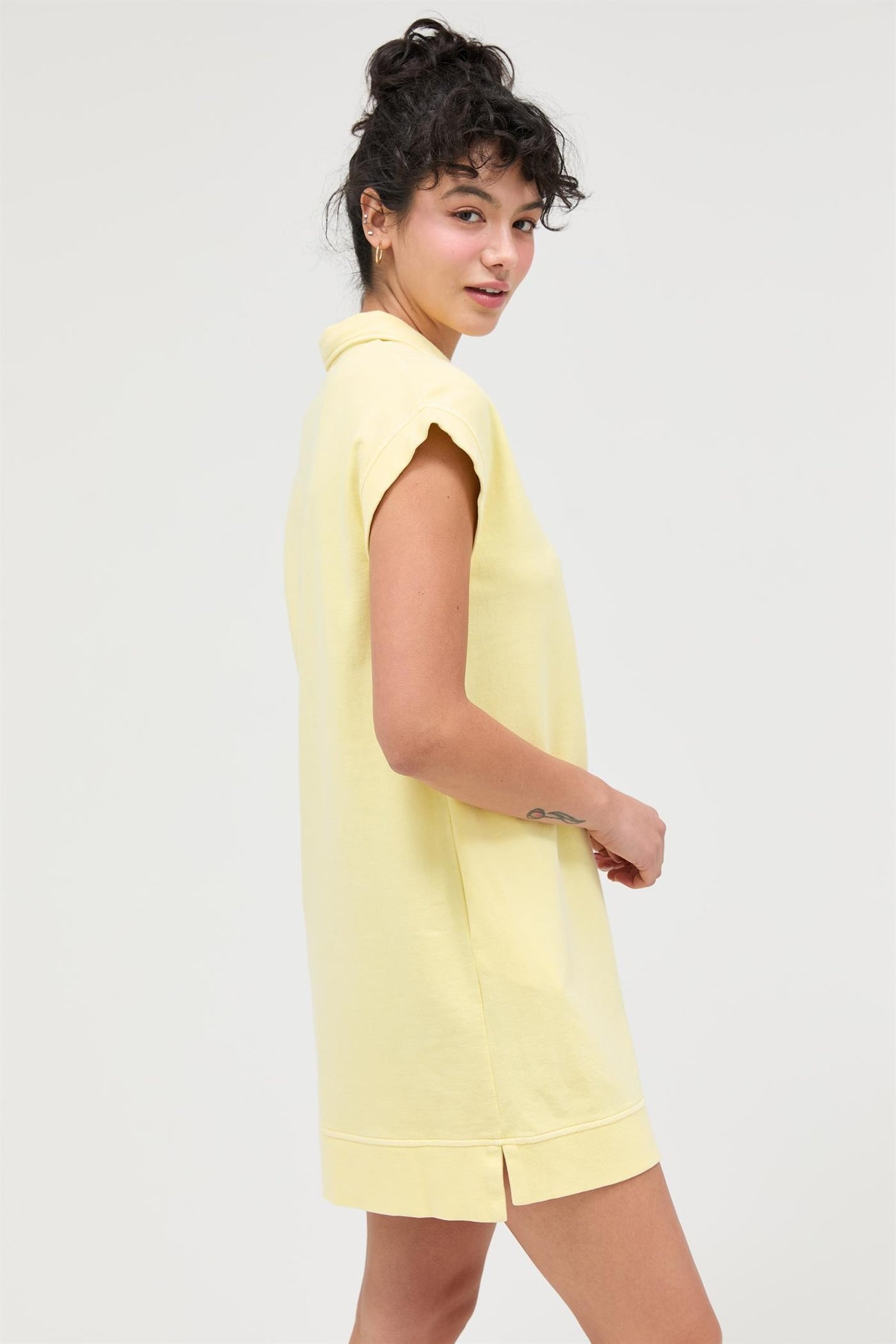 woman wearing a light yellow short sleeve collared dress with side slits