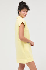 woman wearing a light yellow short sleeve collared dress with side slits