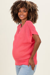woman wearing a bright pink maternity sweater with short sleeves and a visible baby bump