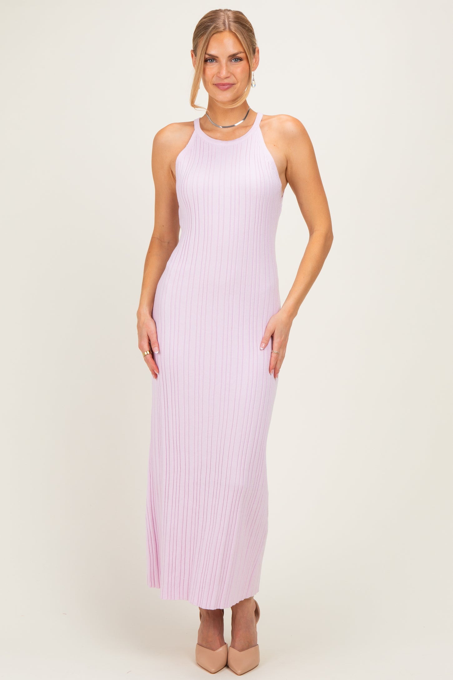 woman wearing a light pink ribbed maxi dress with a halter neck and fitted style